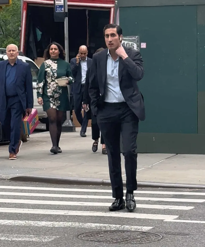 Chirayu Rana in a suit and light blue shirt, crossing the street.