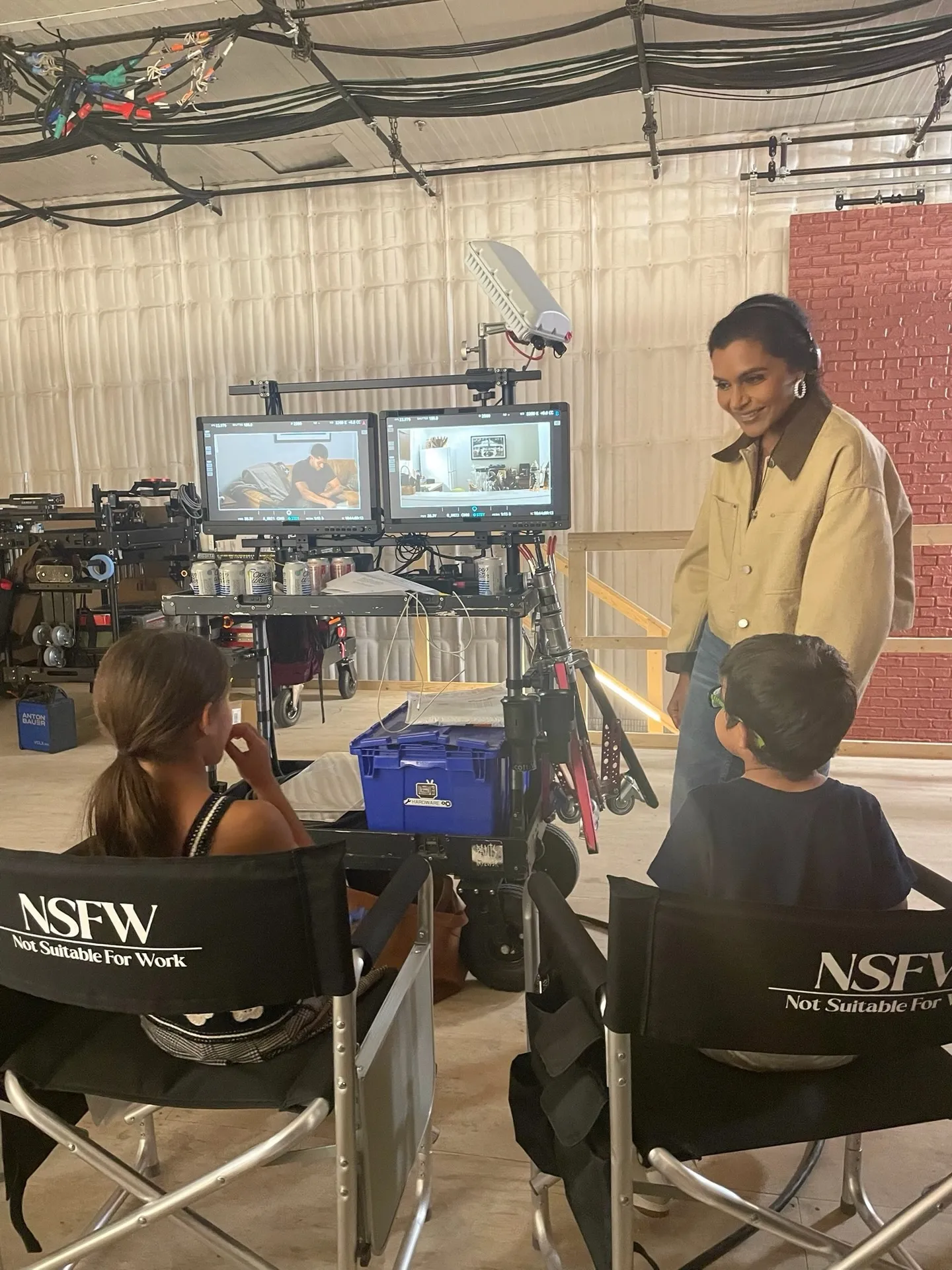 Mindy Kaling on set with her children in director's chairs watching playback.
