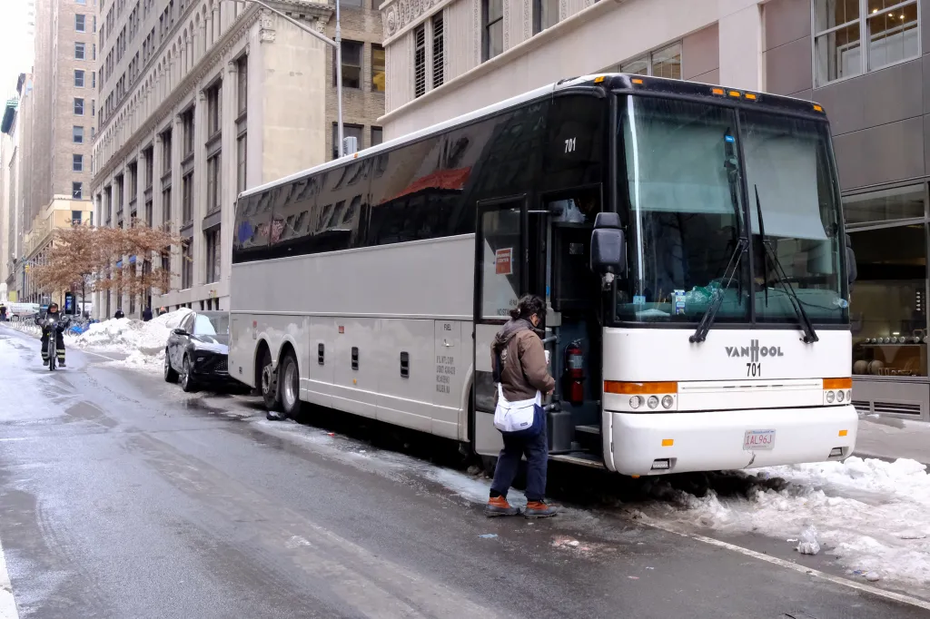 A white bus labeled "Warming Center" with a person entering it on a snowy street.