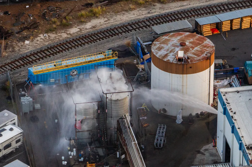 Aerial view of water being sprayed onto chemical tanks at an aerospace plant.