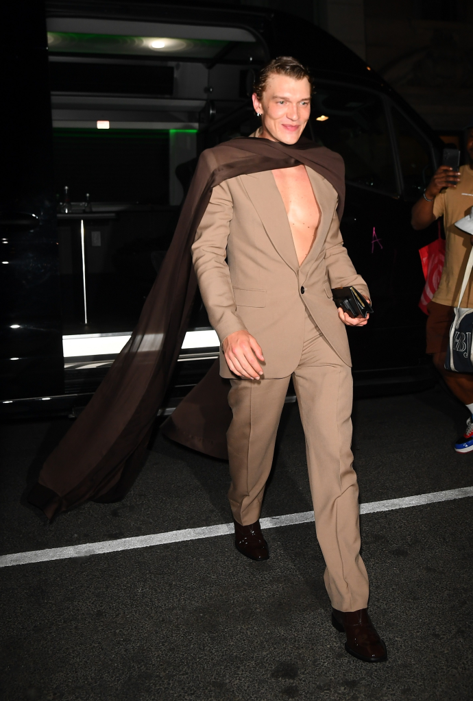 Connor Storrie at the GQ Met Gala after-party in NYC, wearing a tan suit with a dark brown sheer cape.