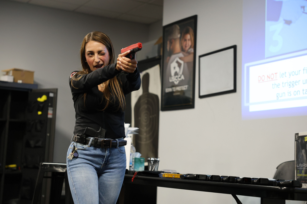Georgia Worrell from the NY Post winks while aiming a red training pistol during a "Pistols & Pilates" class.