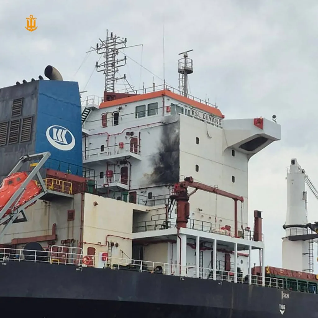 The KSL Deyang cargo ship, with "KSL DEYANG" visible on its white structure, shows black smoke damage on its side.