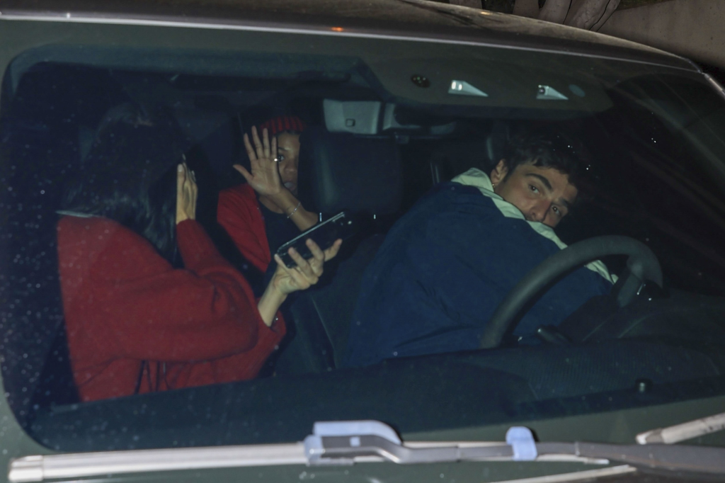 Jacob Elordi driving with Kendall Jenner in the passenger seat and Kylie Jenner and another person in the back seat, with the person in the back covering their face.