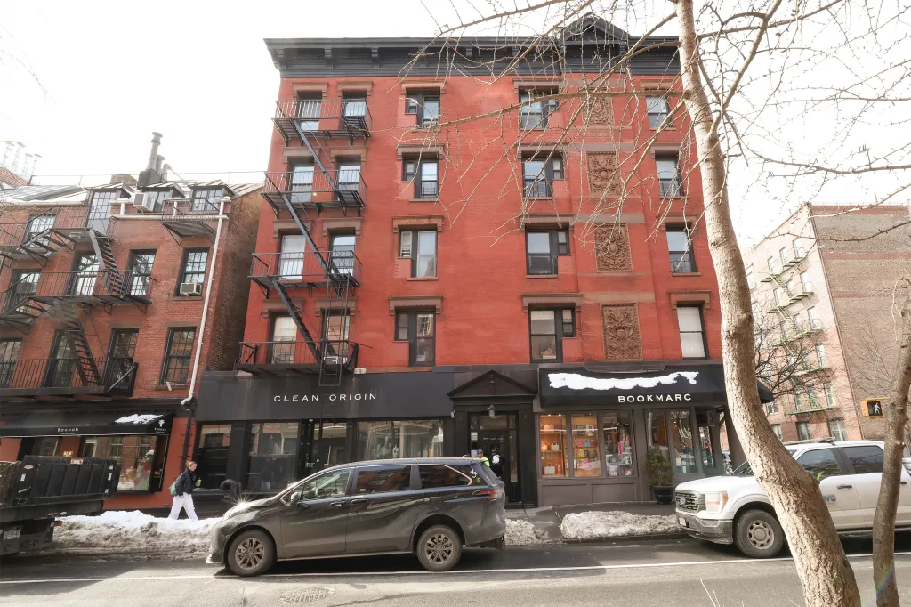 The facade of 400 Bleeker Street in the West Village, a brick building with fire escapes and storefronts.