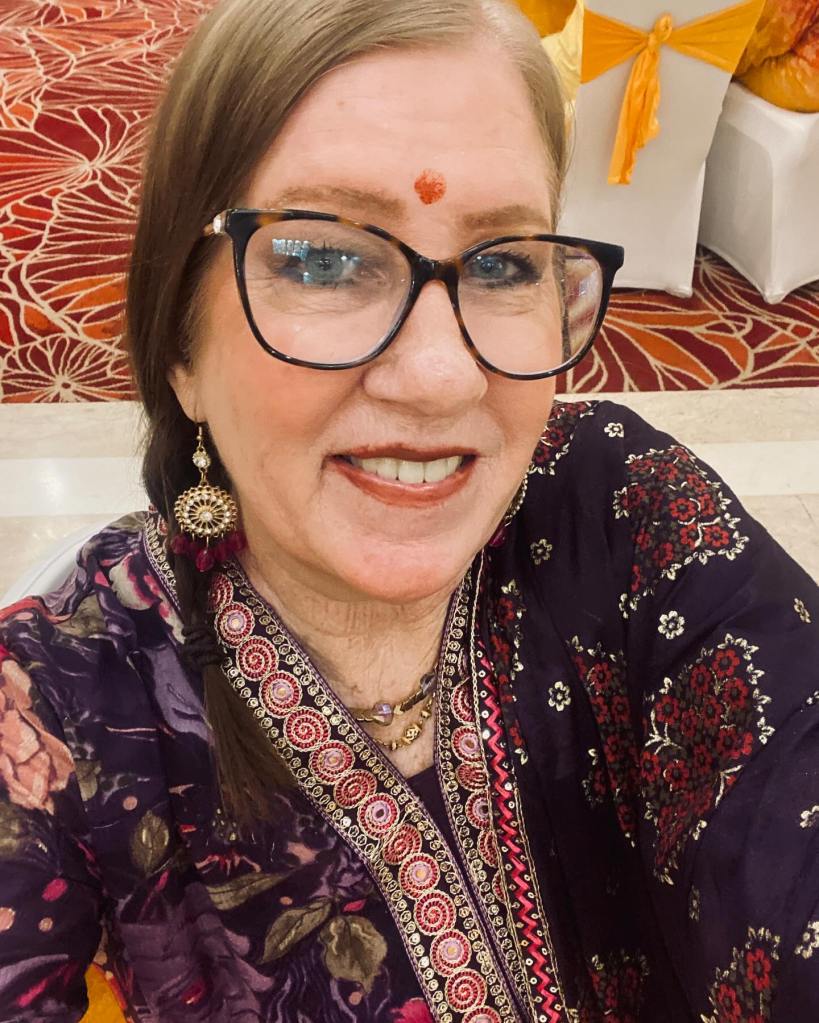 Jenny Slatten from '90 Day Fiance' smiles wearing glasses and traditional Indian clothing.