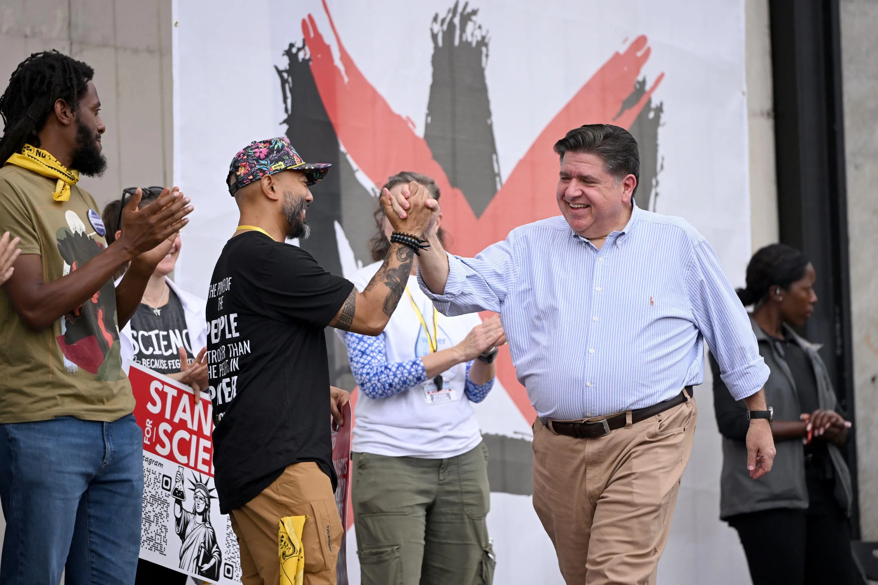 JB Pritzker giving a high-five to a person onstage JB Pritzker giving a high-five to a person onstage