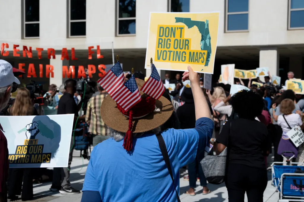 A person at a rally holds a sign that reads 