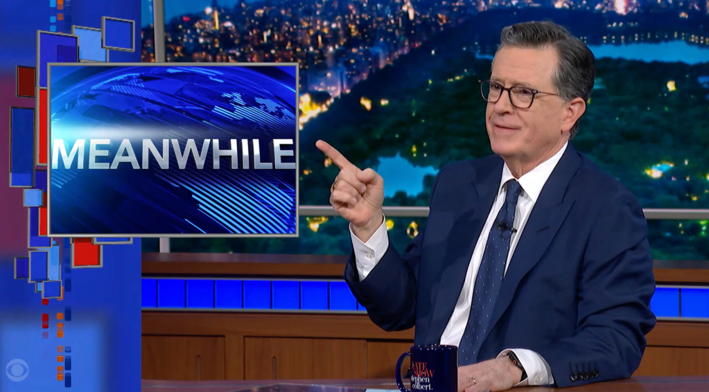 Stephen Colbert pointing at a screen displaying the word "MEANWHILE" on The Late Show.