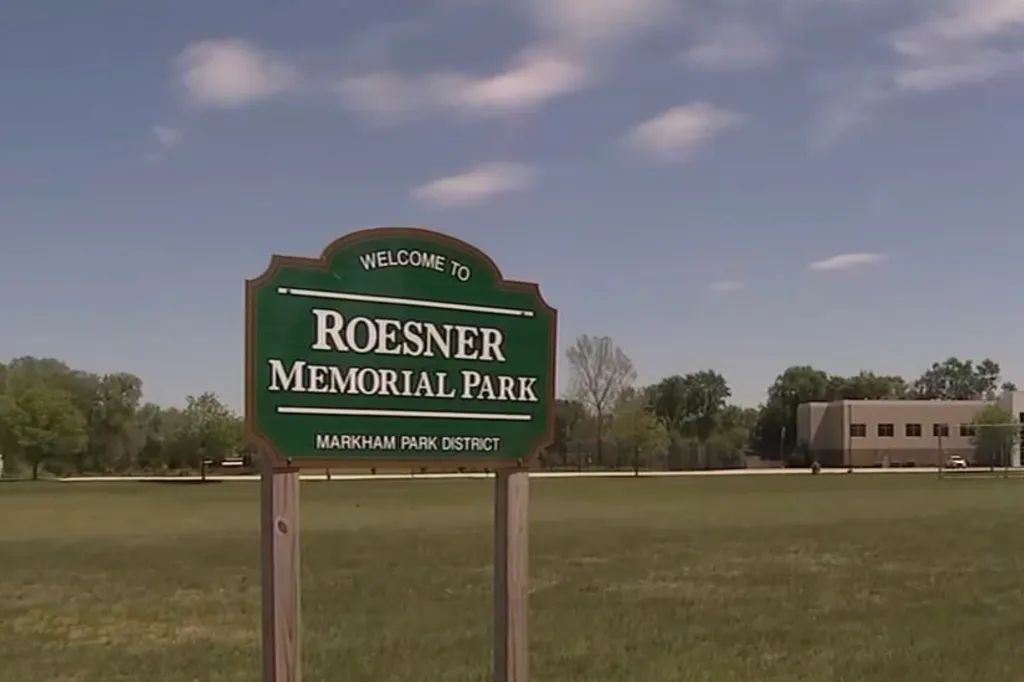 "Welcome to Roesner Memorial Park" sign in front of a grassy field.