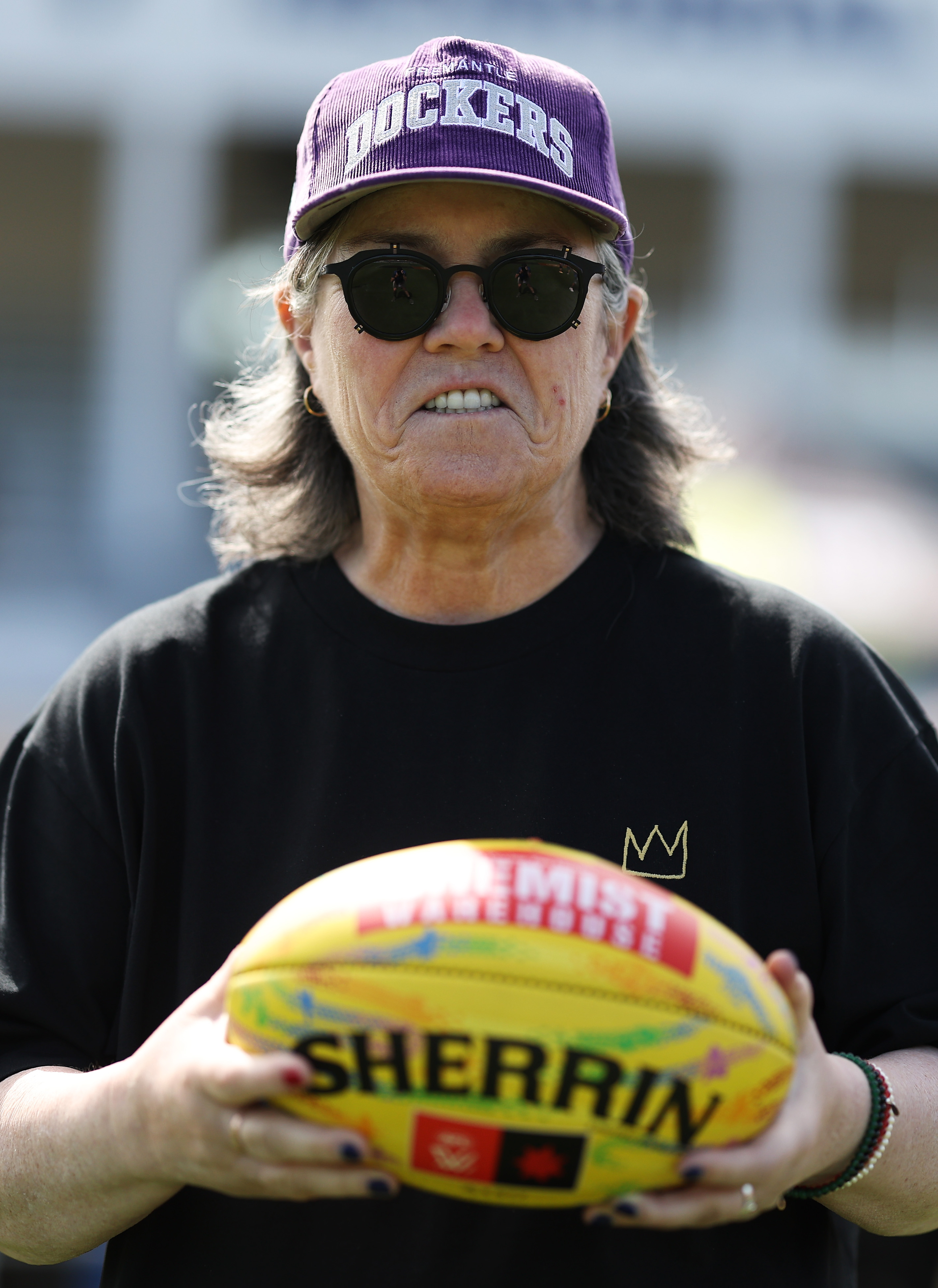 Rosie O'Donnell holding a yellow Sherrin football.