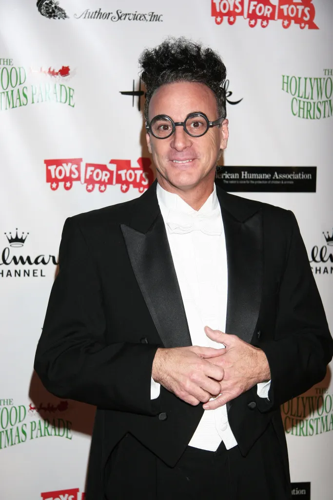 Ed Alonzo, wearing a tuxedo with a white bow tie and round glasses, attends the 80th anniversary Hollywood Christmas parade.