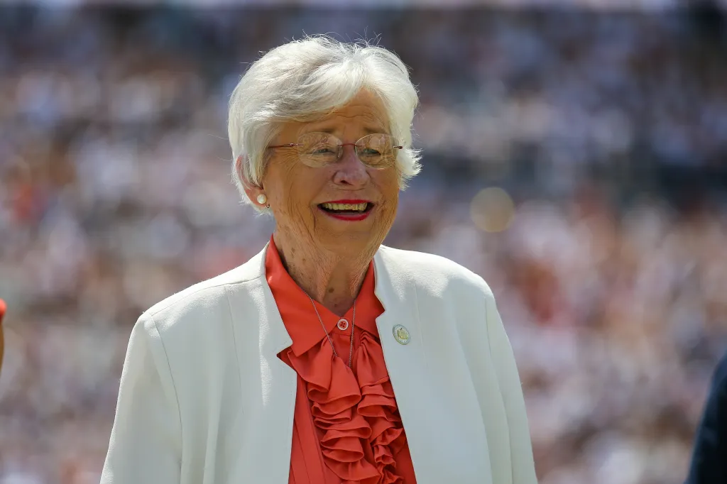 Alabama Governor Kay Ivey smiling during homecoming ceremonies at a football game.