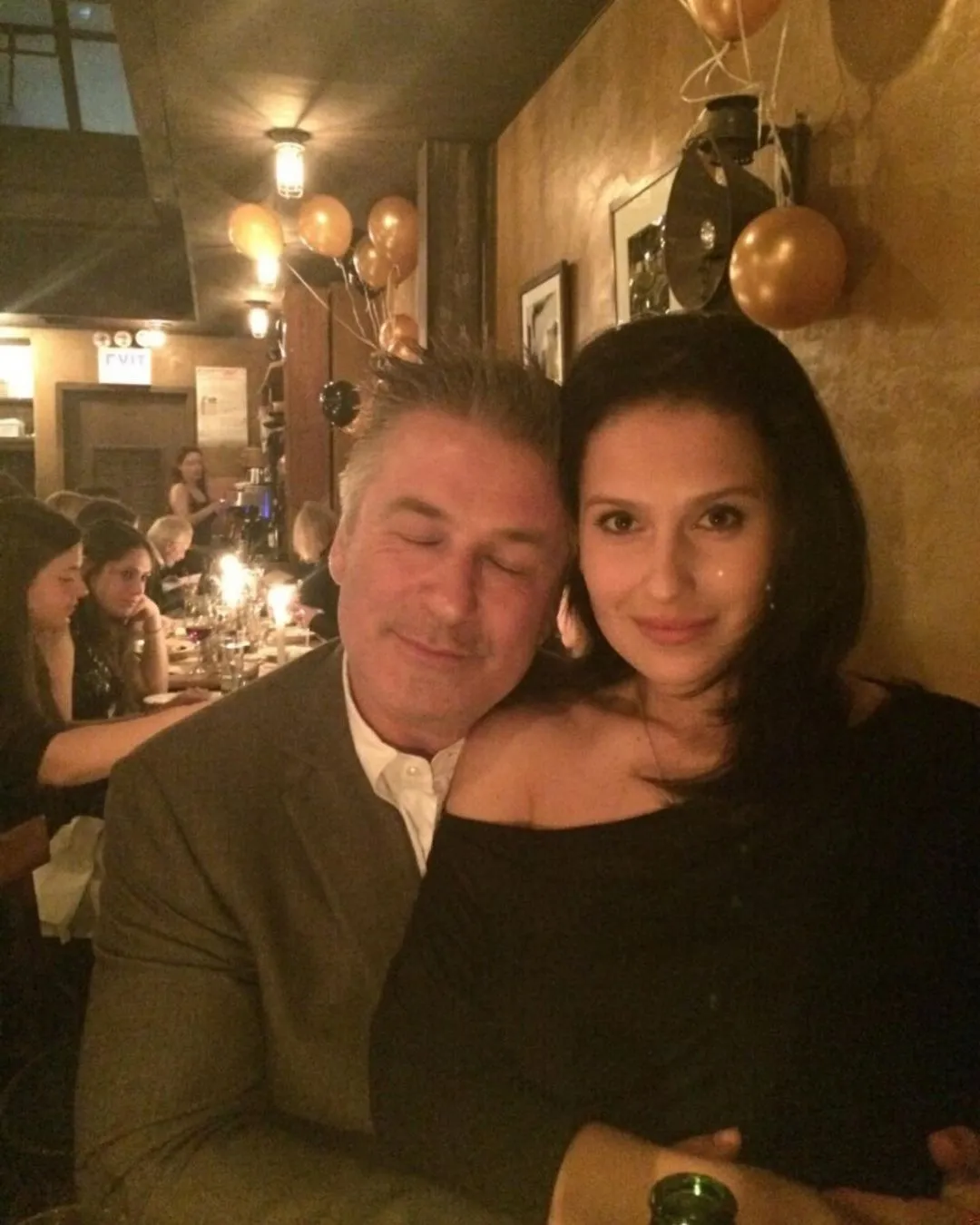 Alec and Hilaria Baldwin posing at a dinner party.
