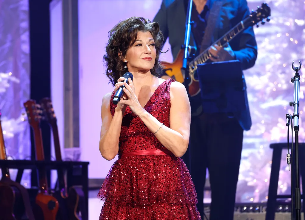 Amy Grant singing into a microphone at the Ryman Auditorium.