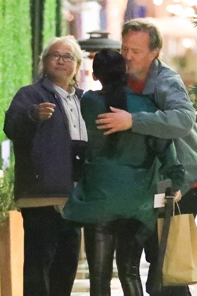 Matthew Perry embracing a woman while Kenneth Iwamasa looks on.