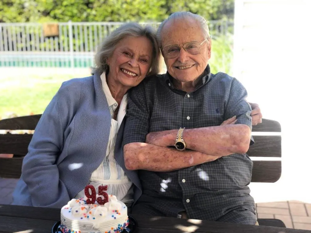 William Daniels and Bonnie Bartlett smiling with a 95th birthday cake.