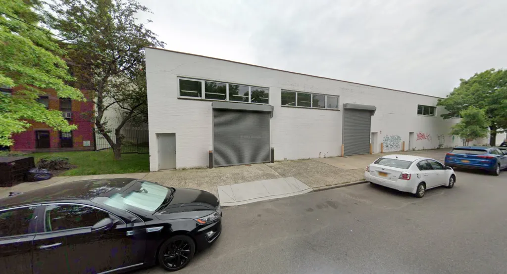 Street view of a white brick building at 46 President St with two garage doors.