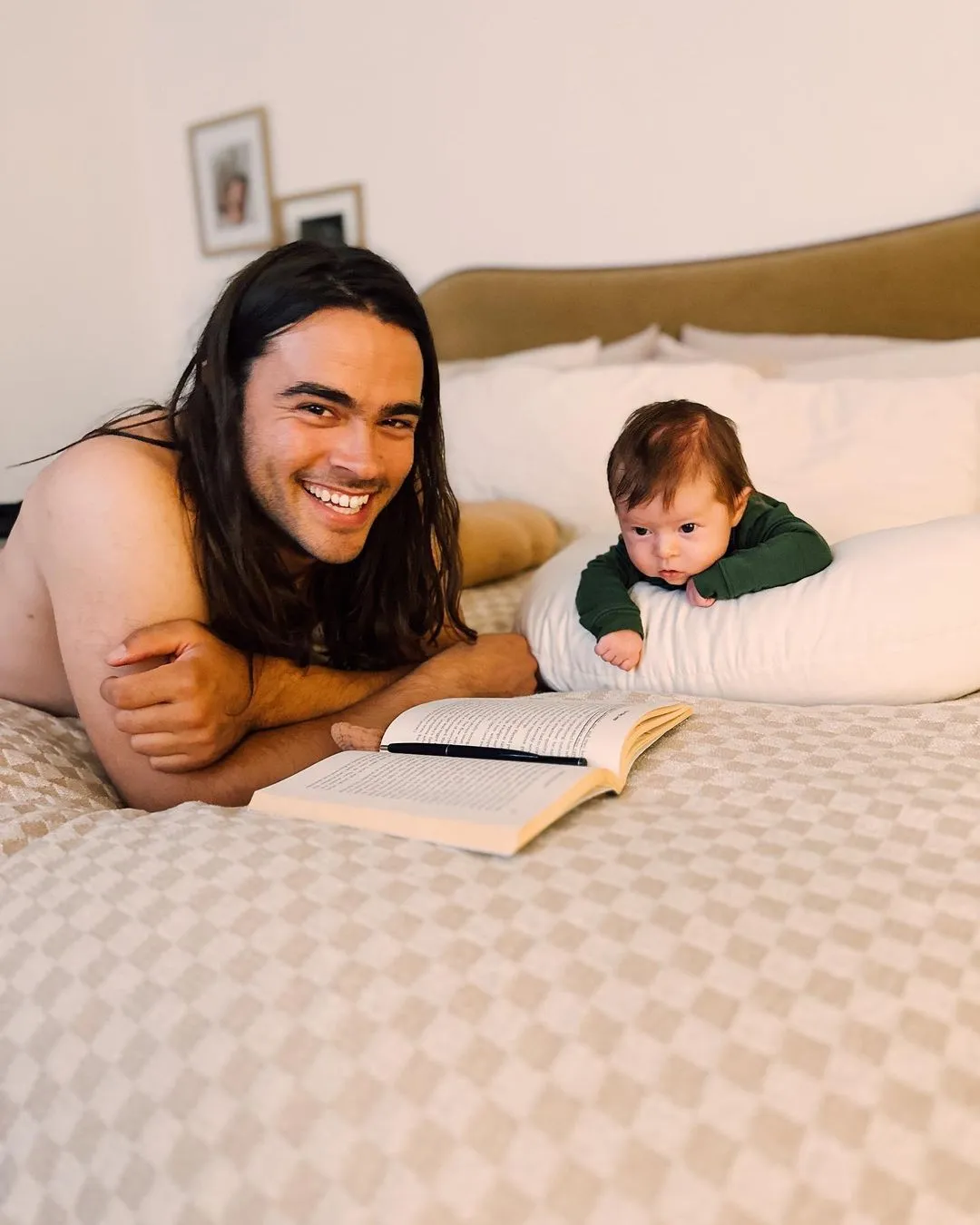 Derek Richard Thomas and Louetta are on a bed, with Derek smiling at the camera and Louetta looking curious while lying on a pillow.