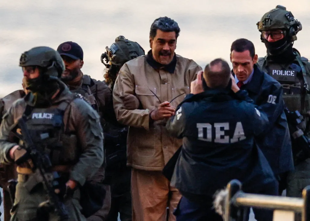 Venezuelan President Nicolas Maduro, in a light brown outfit, is surrounded by law enforcement officers, some with "POLICE" and "DEA" visible on their clothing, appearing to be apprehended.