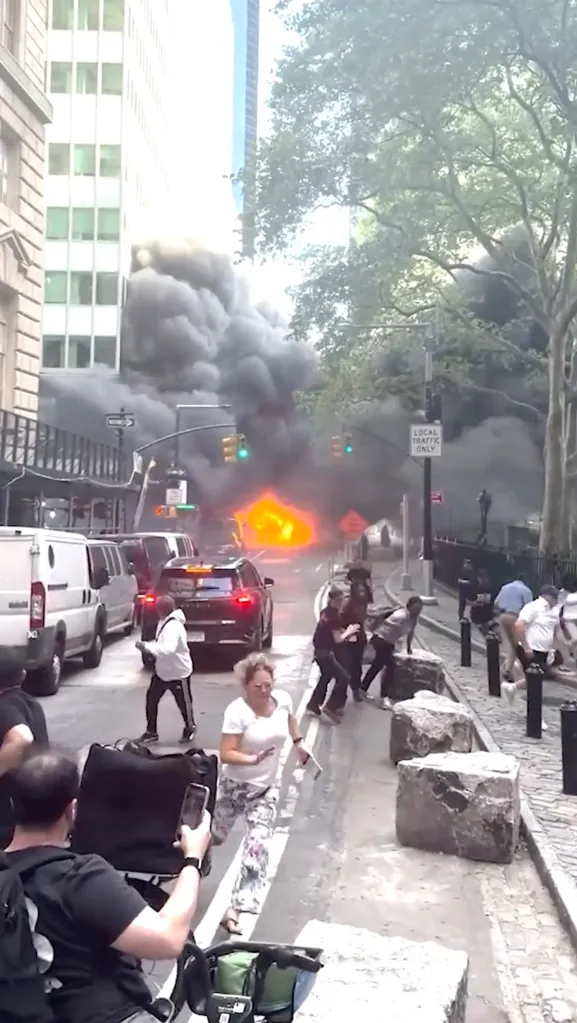 People running from an exploding car, with thick black smoke and flames filling the street in Lower Manhattan.