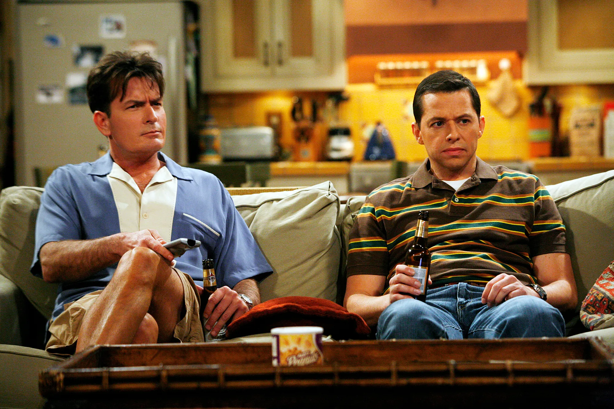 Charlie Sheen (left) and Jon Cryer (right) sit on a couch in a scene from "Two and a Half Men."