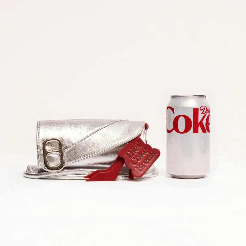 Silver "Canny Pack" clutch with a red "Diet Coke Break" tag next to a Diet Coke can.