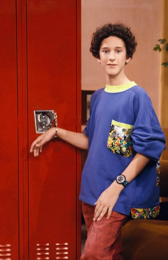 Dustin Diamond as Screech Powers with his arm cuffed to a red locker.