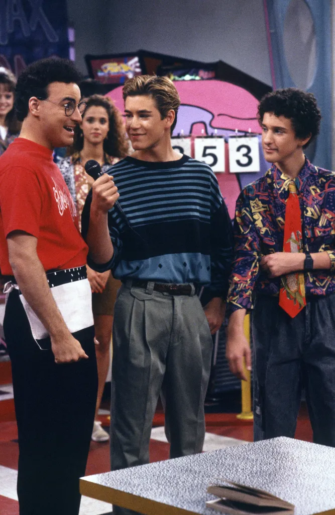 Ed Alonzo, Mark-Paul Gosselaar, and Dustin Diamond smiling and holding a microphone while standing in The Max diner.