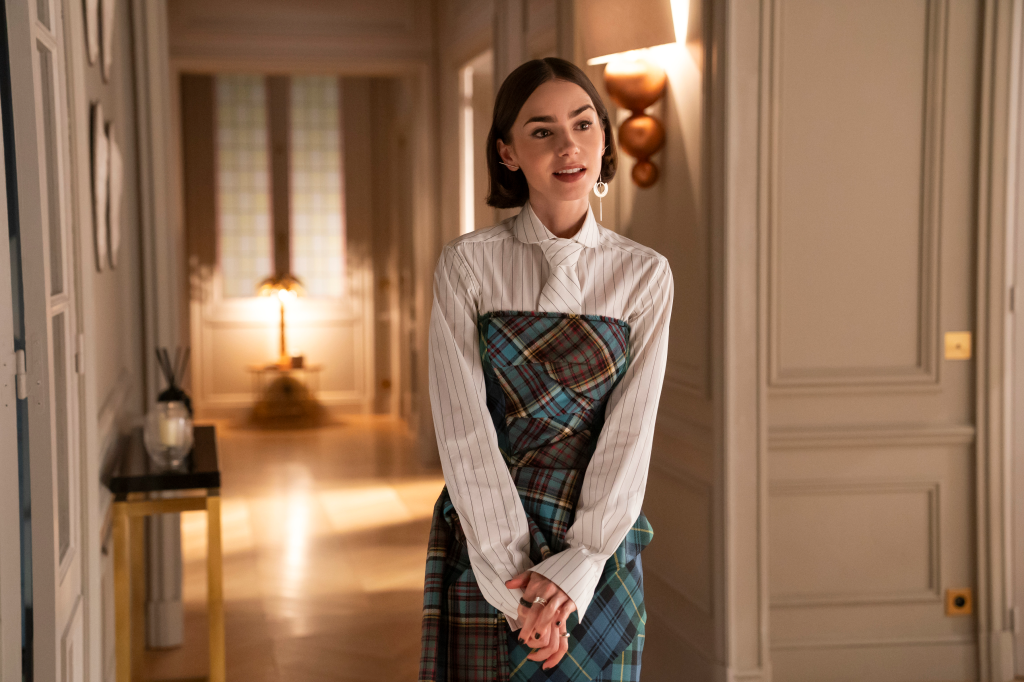 Emily in Paris, played by Lily Collins, wearing a plaid dress over a striped shirt.