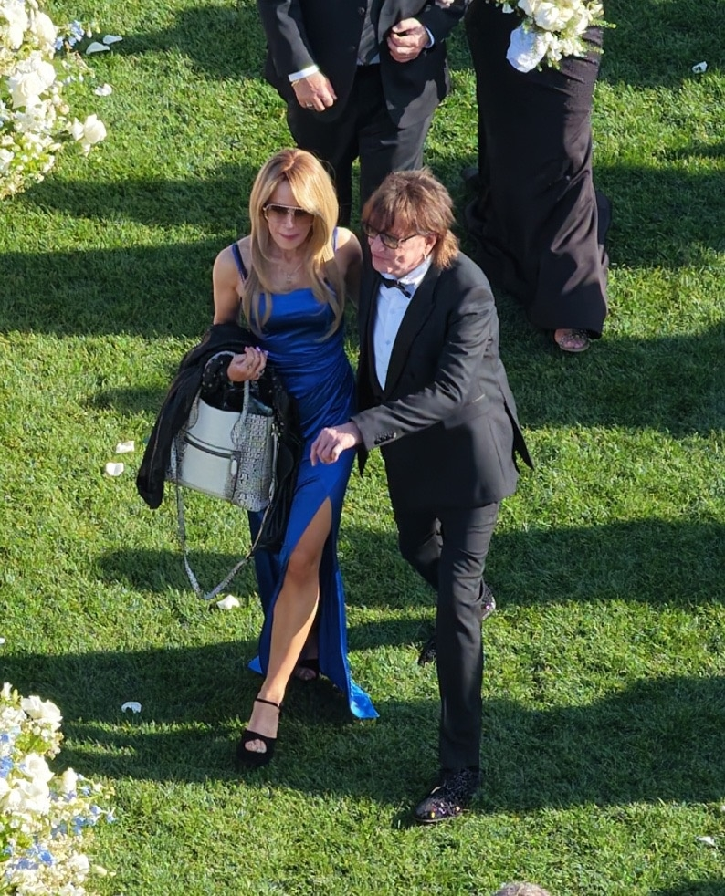 Richie Sambora in a black tuxedo walking next to a woman in a royal blue dress.