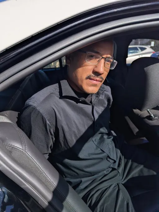 Michael Angel Alvarez, arrested by the FBI, sitting in the backseat of a car.