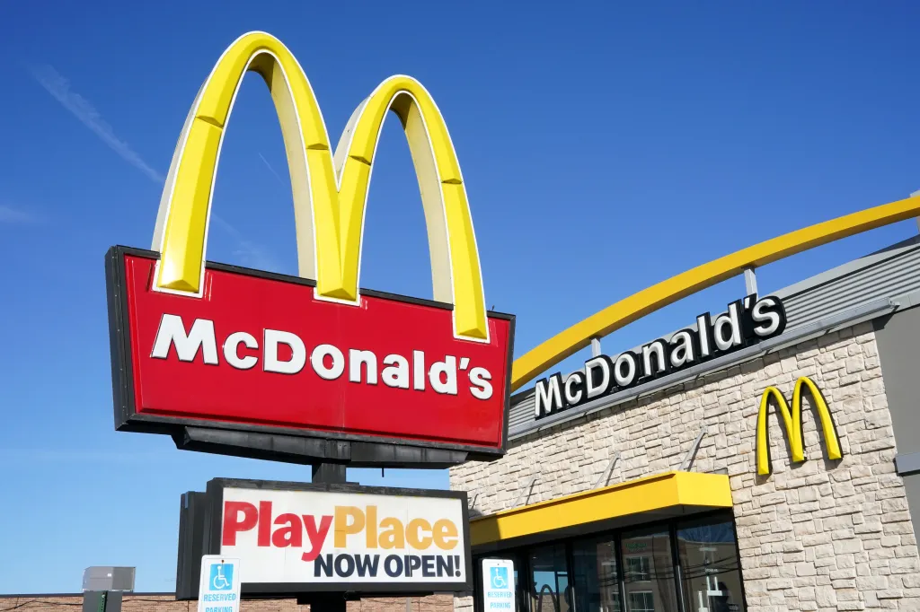 A McDonald's restaurant sign with golden arches and a sign below reading 
