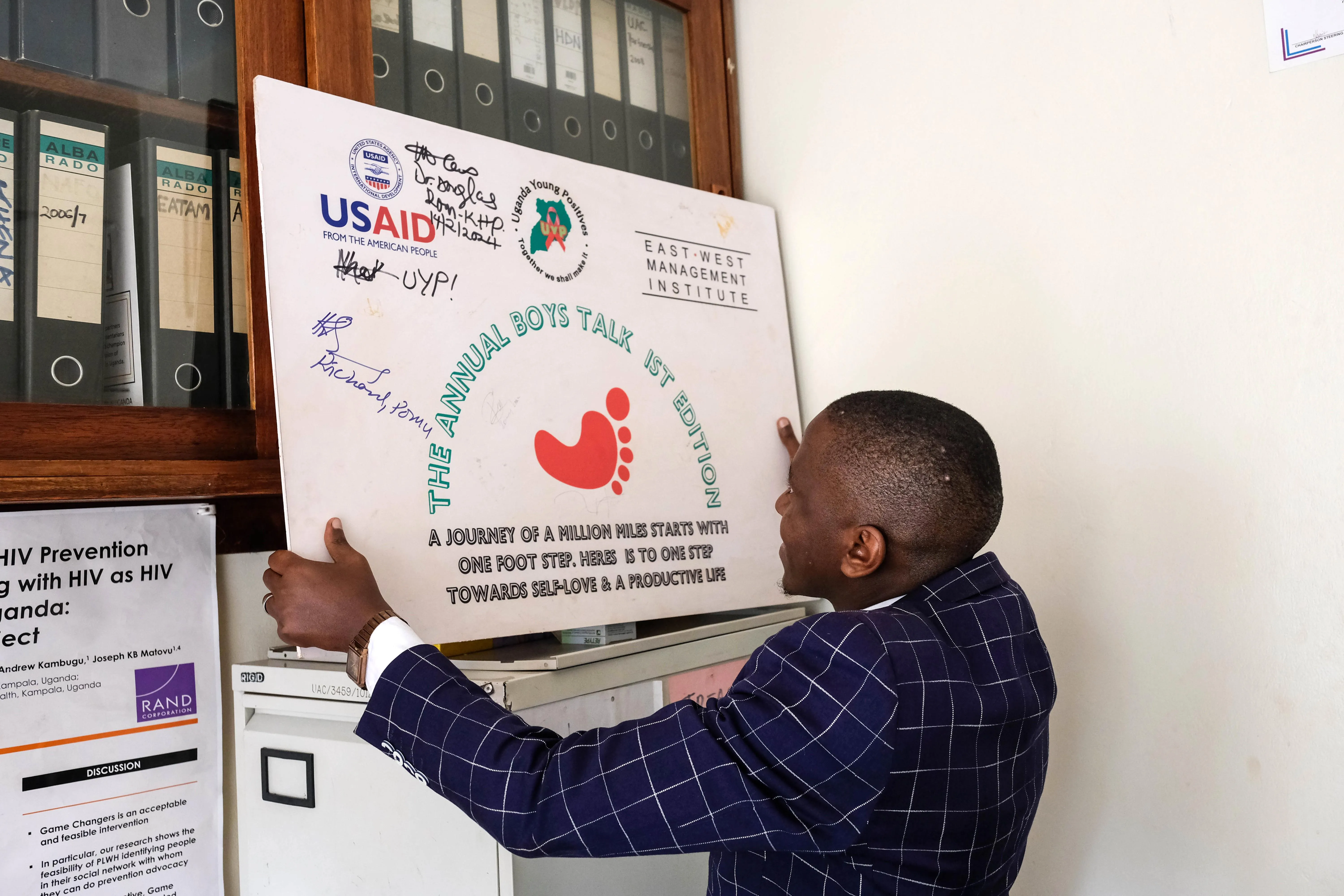 A staff member at an HIV outreach organization holds a poster inscribed with the USAID logo.