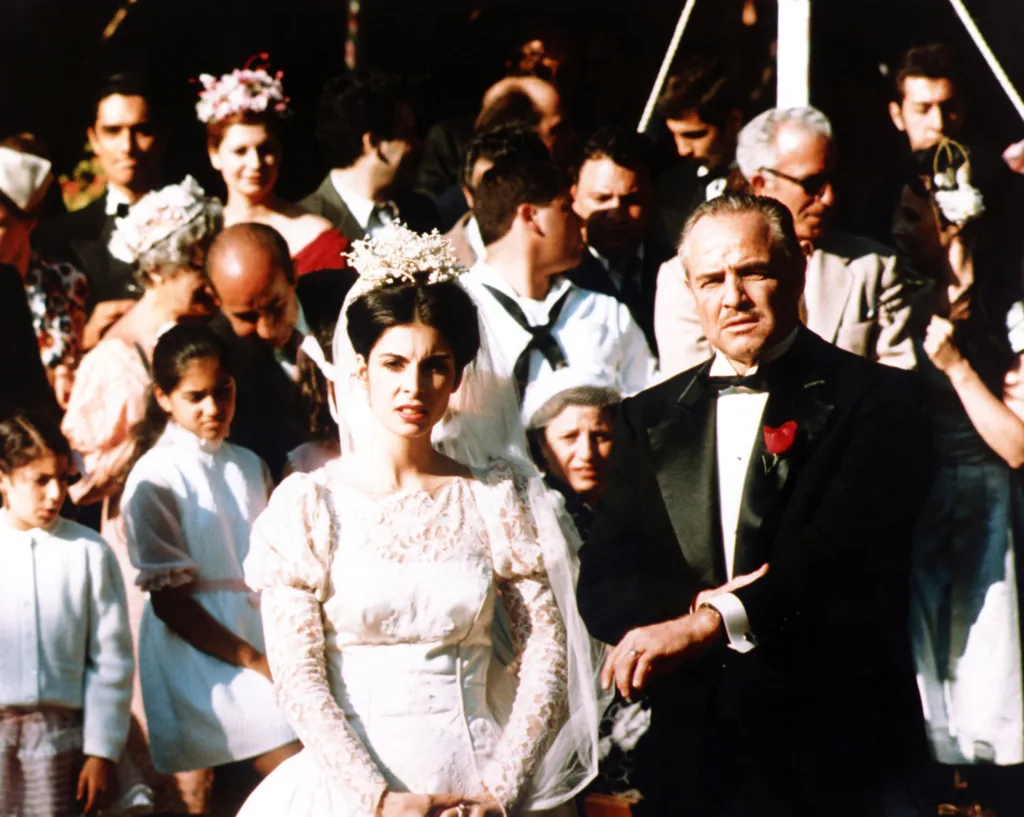 Marlon Brando as Don Corleone stands next to Talia Shire as Connie Corleone in her wedding dress, in the film "The Godfather".
