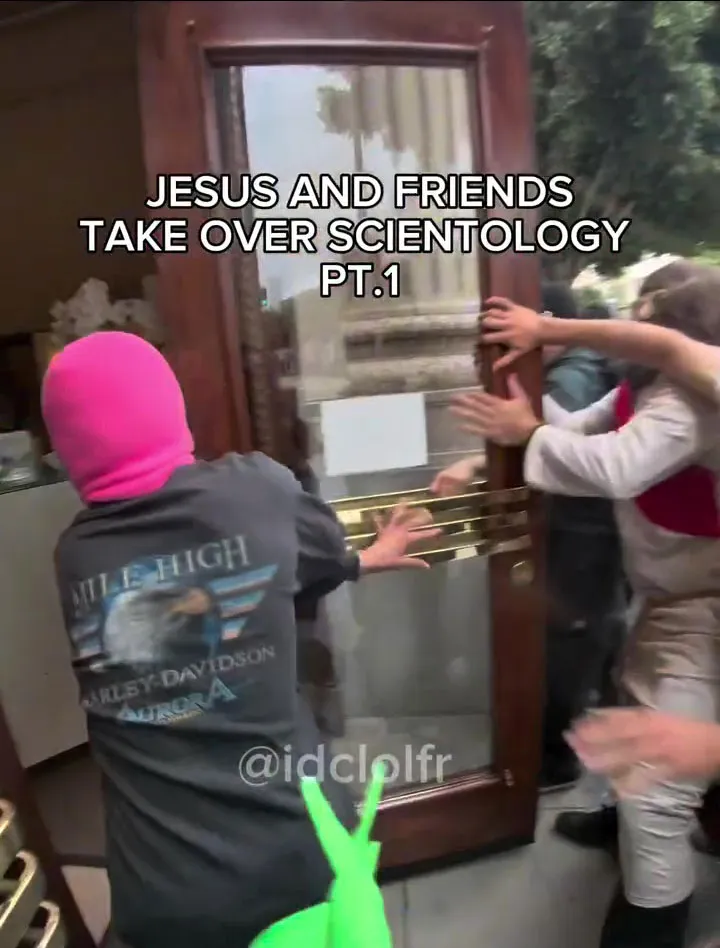 People attempting to force open a glass door of a Scientology building.