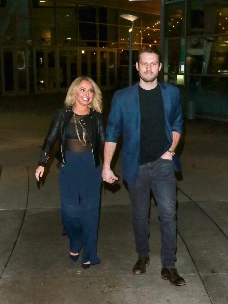 Hayden Panettiere wearing a black leather jacket and wide-leg pants, holding hands with Brian Hickerson in a blazer and jeans.