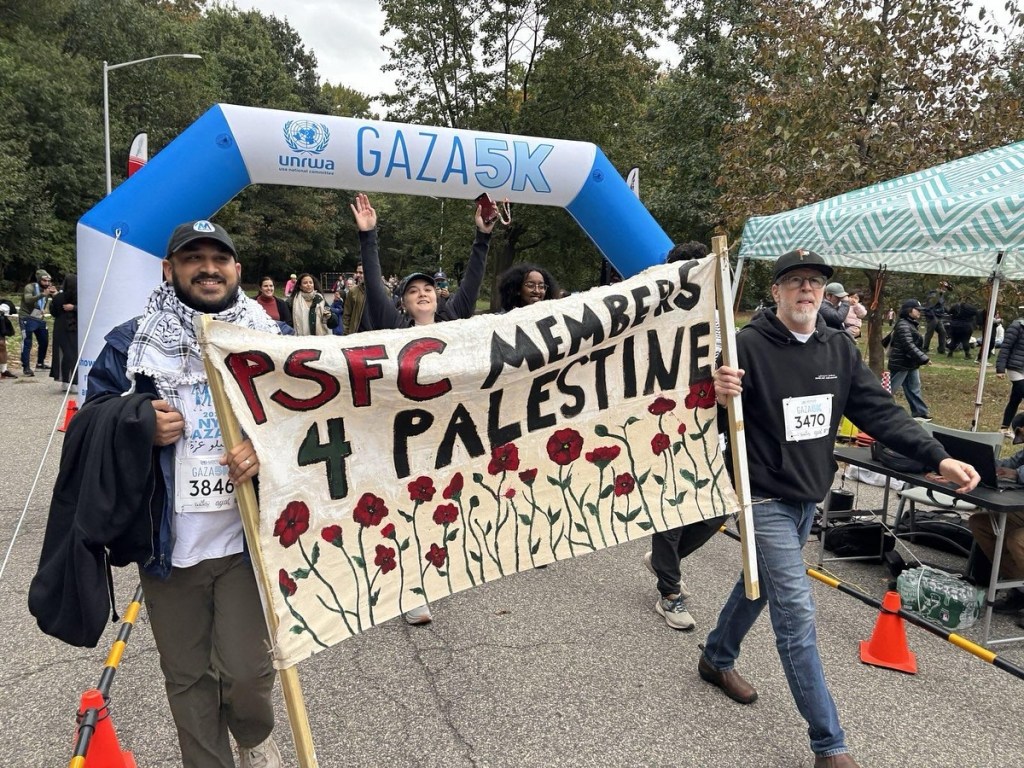 People march under a banner reading "PSFC 4 PALESTINE" at a Gaza 5K event.