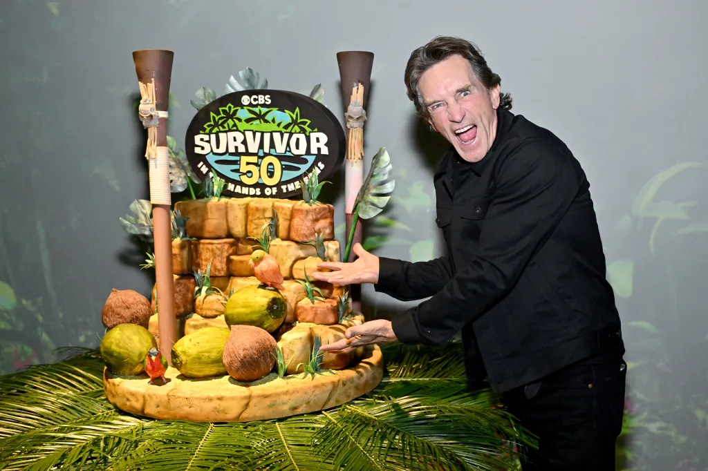 Jeff Probst with an excited expression next to a "Survivor 50" themed cake.