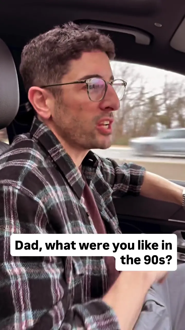 Jason Biggs driving a car, wearing a plaid shirt and glasses, with the text "Dad, what were you like in the 90s?"
