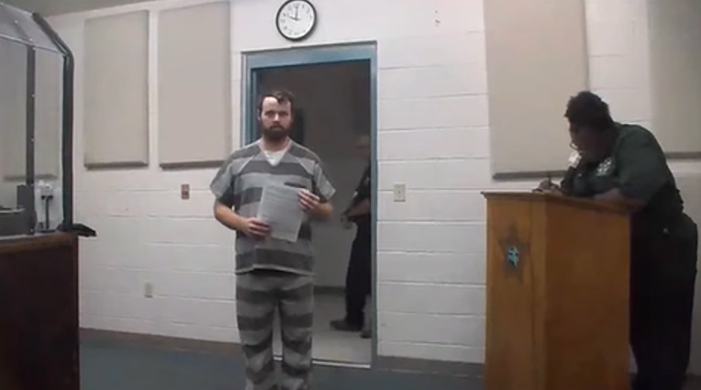 Joseph Duggar in a striped prison uniform in a courtroom.
