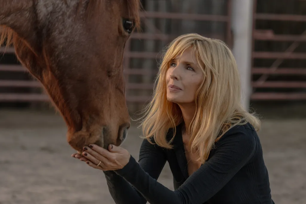 Beth Dutton cradling a horse's muzzle in her hands.