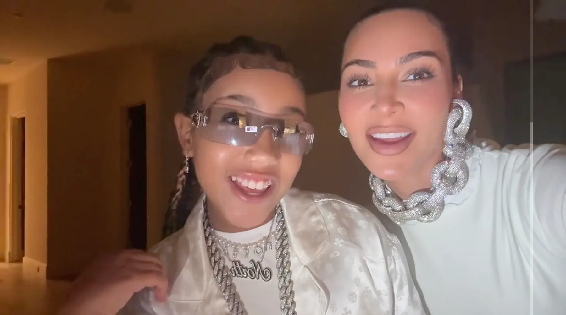 Kim Kardashian and North West smiling and wearing all-white ensembles.