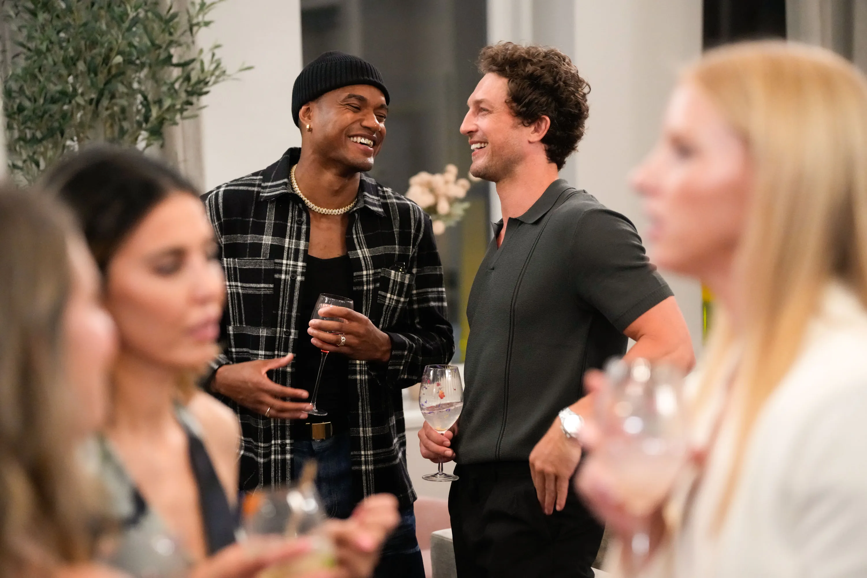 Two men, KJ Dillard and Ben Waddell, smiling and holding drinks at an indoor event.