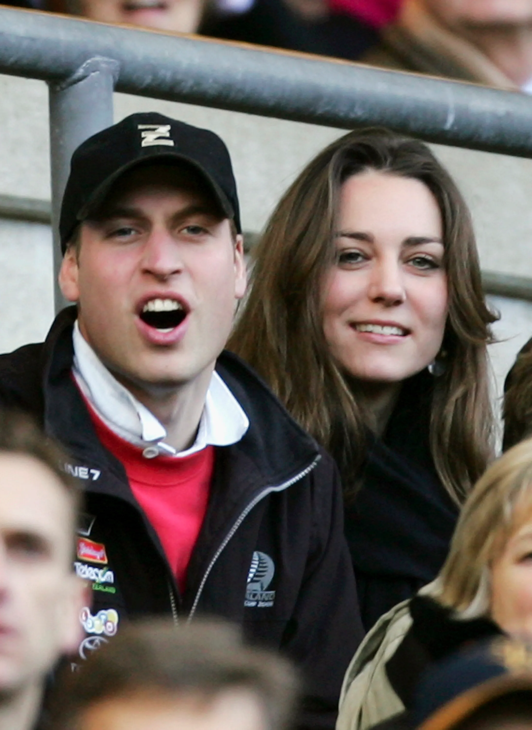 Prince William wearing a cap and Kate Middleton watching a rugby match.