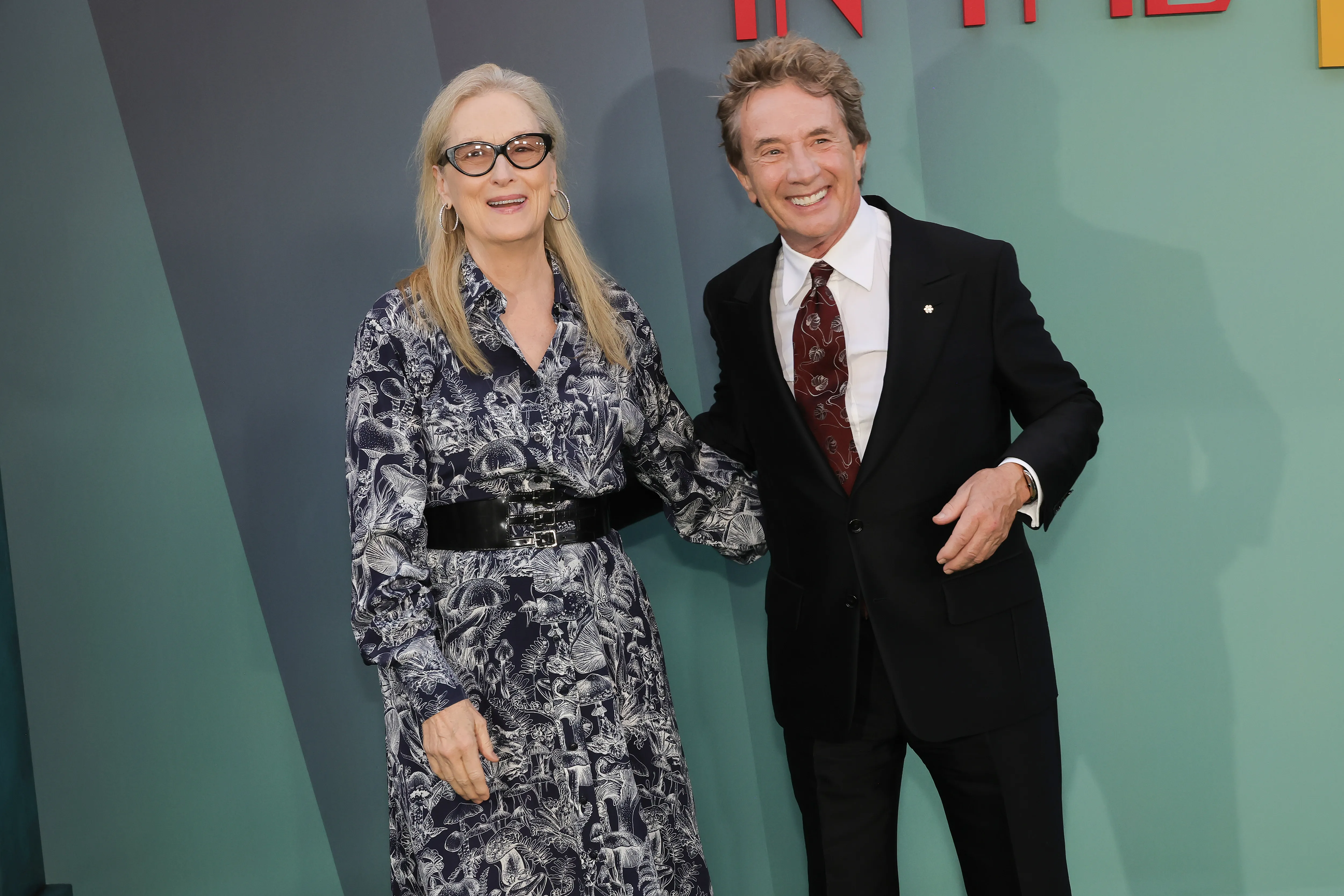 Meryl Streep in a patterned dress and Martin Short in a suit smiling.