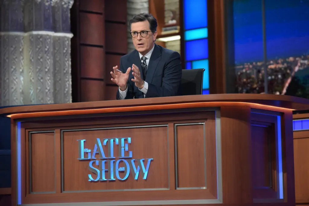 Stephen Colbert speaking at his desk on the set of The Late Show.