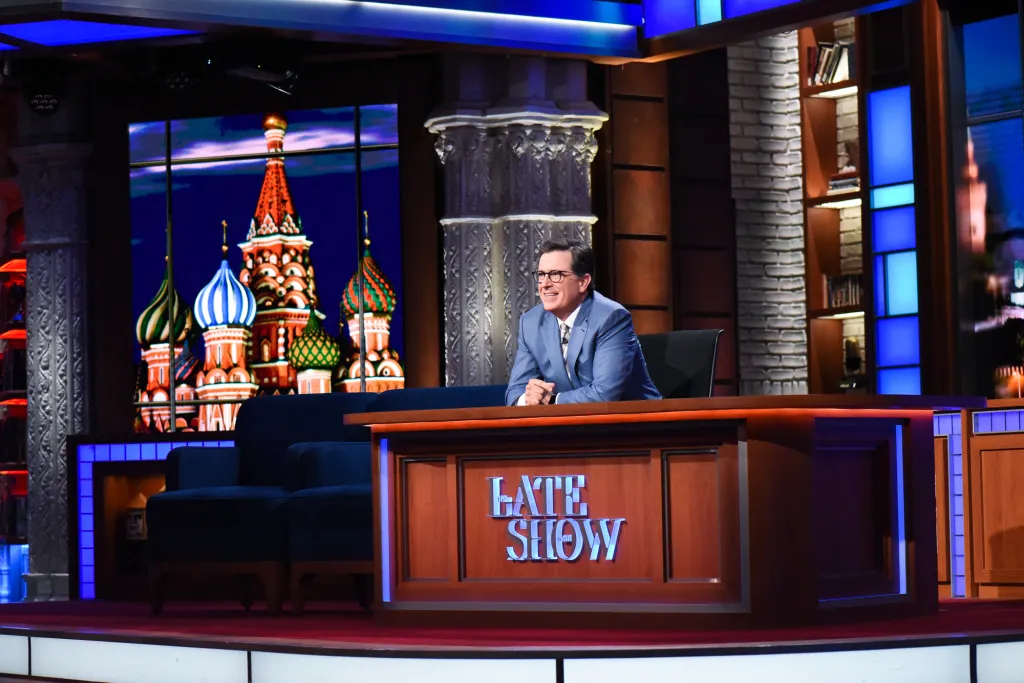 Stephen Colbert on the set of The Late Show with a backdrop of St. Basil's Cathedral.