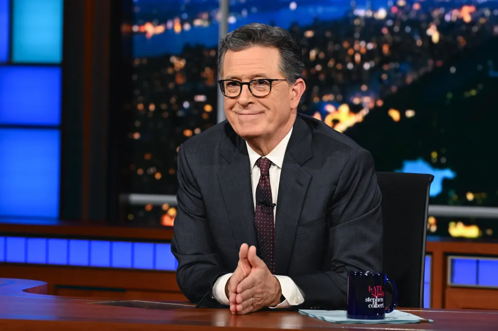 Stephen Colbert sits at his desk on the set of The Late Show.