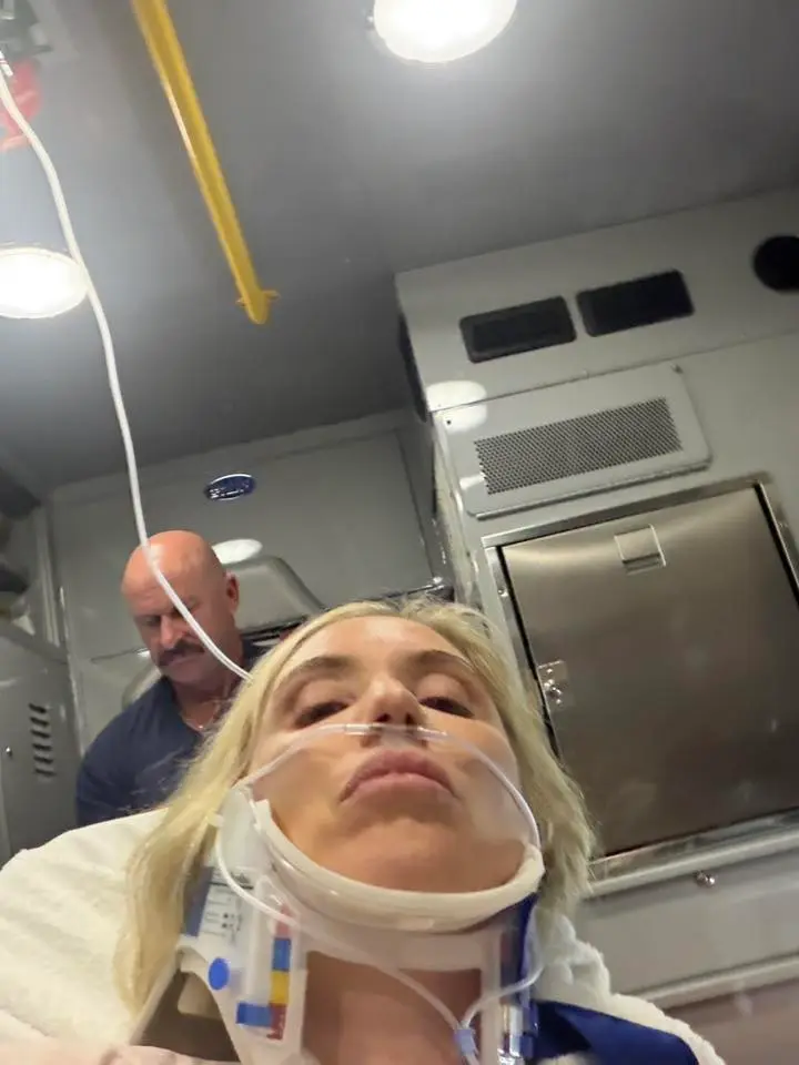 Laura Clery in an ambulance with a neck brace and oxygen tubes.
